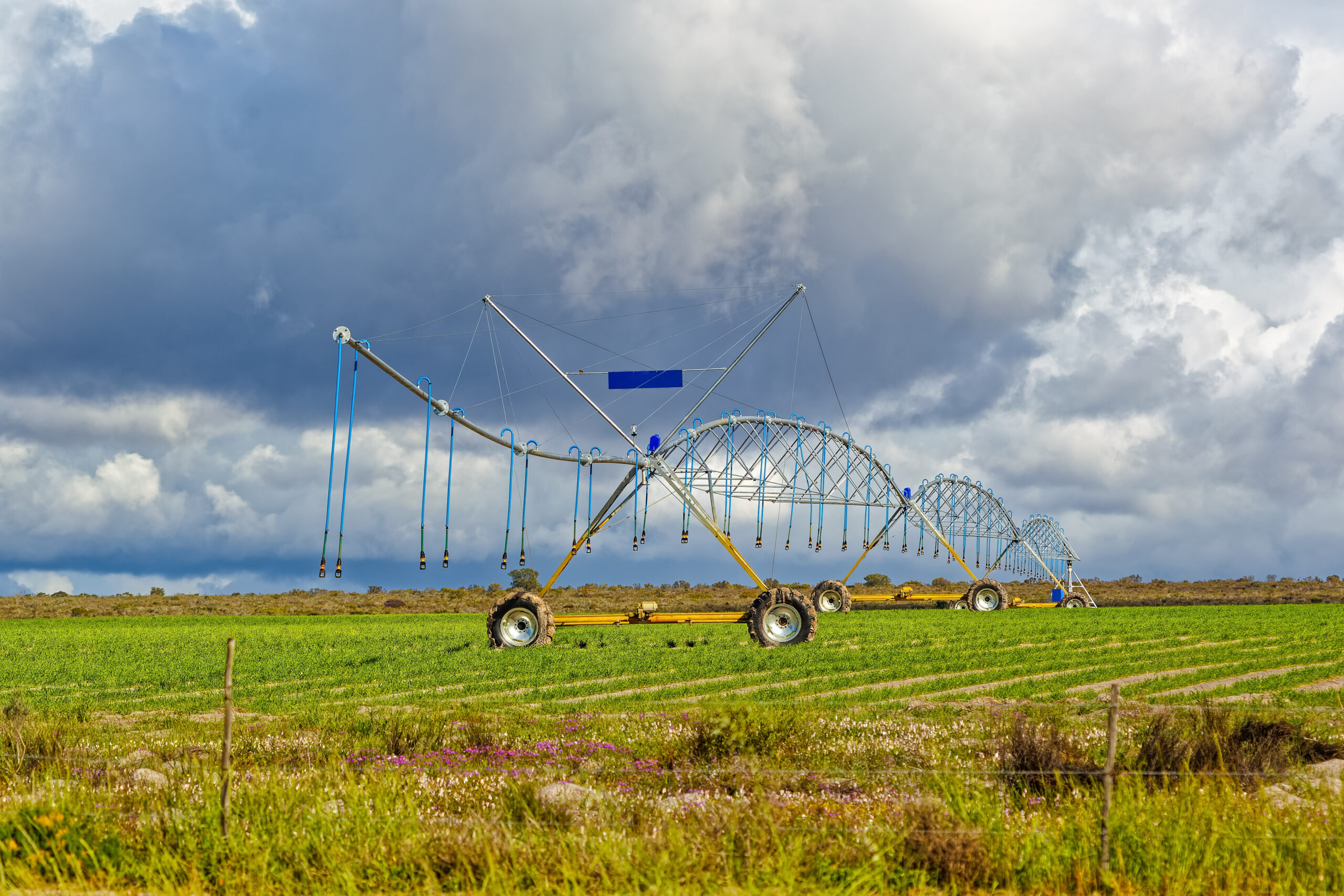 Three-quarter view of large irrigation sprinkler boom with dark clouds in background in early spring near Hopefield, Western Cape, South Africa